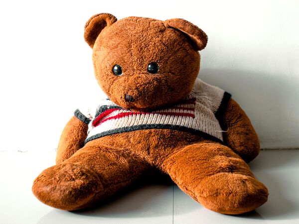 A brown teddy bear in a striped sweater